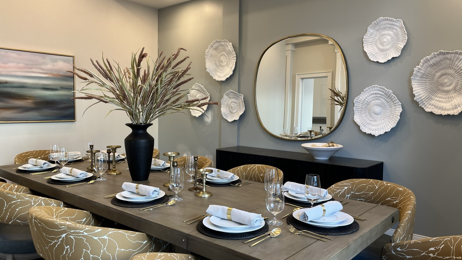 A dining room on installation day — the table fully set, centerpiece, mirror, and wall art all in place
